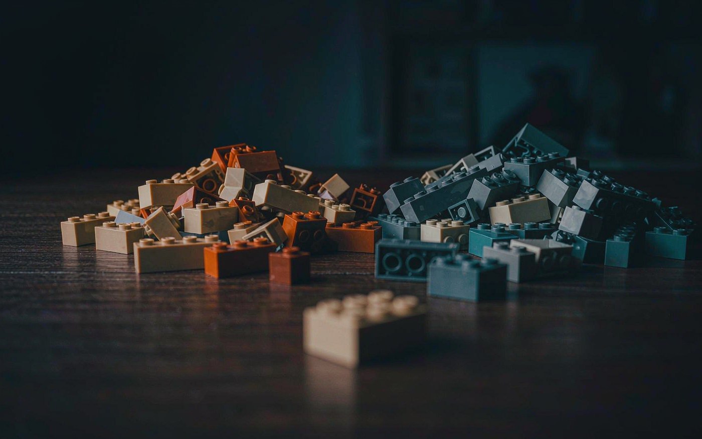 Two piles of plain plastic building bricks in warm and cool tones on a dark wooden table